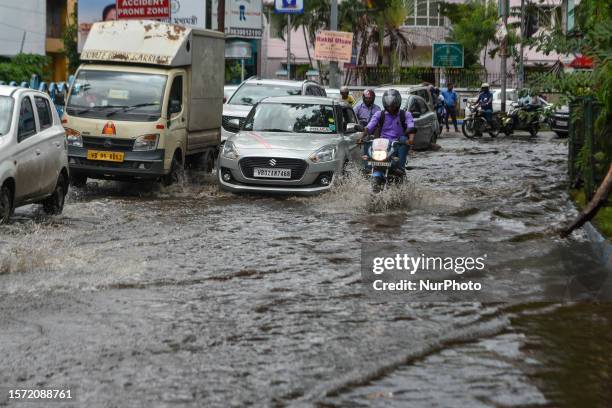 Commuters and office goers are seen making their way through a flooded road in Kolkata , India , on 2 August 2023 . Overnight rain caused many parts...