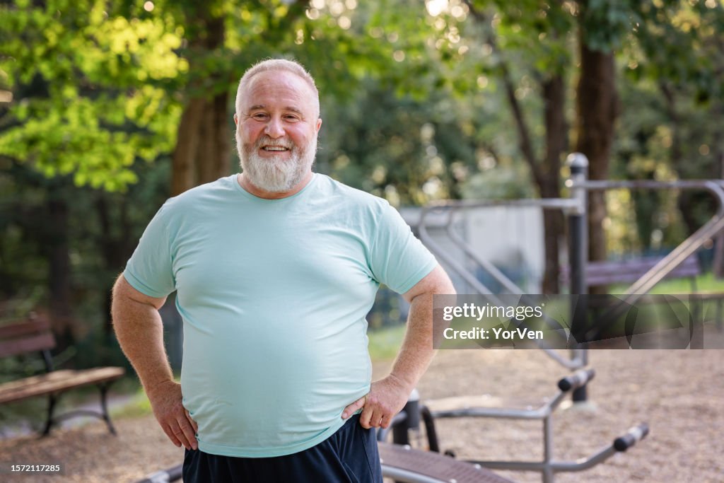 Retrato do homem confiante do excesso de peso positivo do corpo no parque