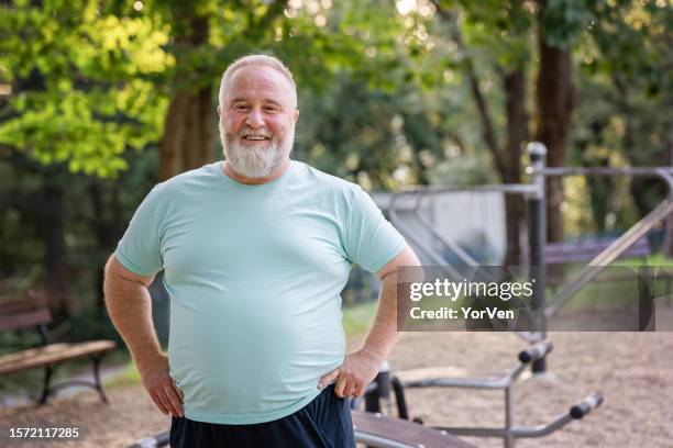 portrait of confident body positive overweight man in the park - fat imagens e fotografias de stock