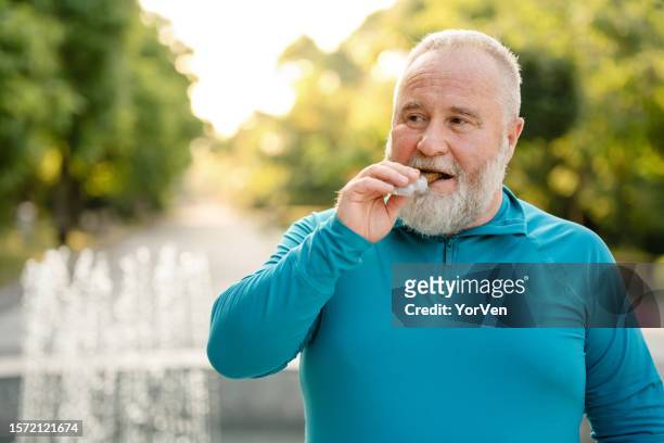 hombre con sobrepeso comiendo una barra de granola saludable - protein bar fotografías e imágenes de stock