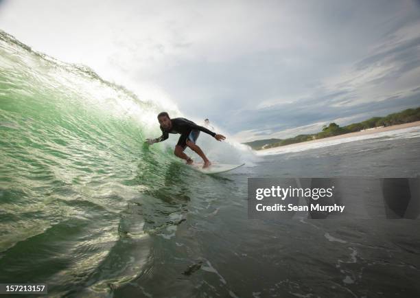 young man surfing down a barrel wave in nicaragua - nicaragua stock pictures, royalty-free photos & images