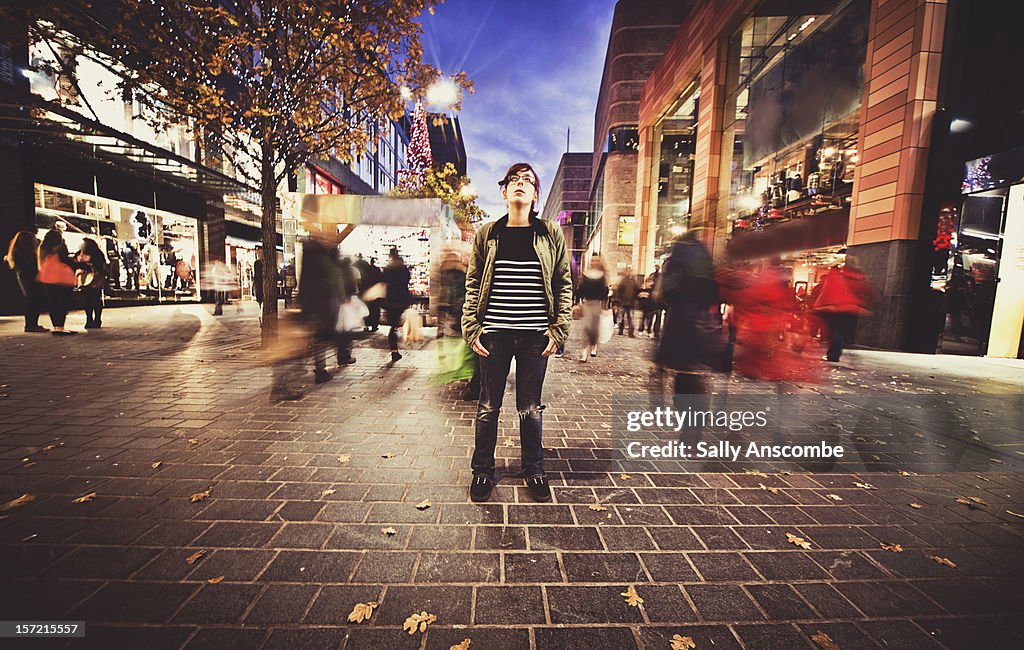 Teenage girl stood still on a busy street