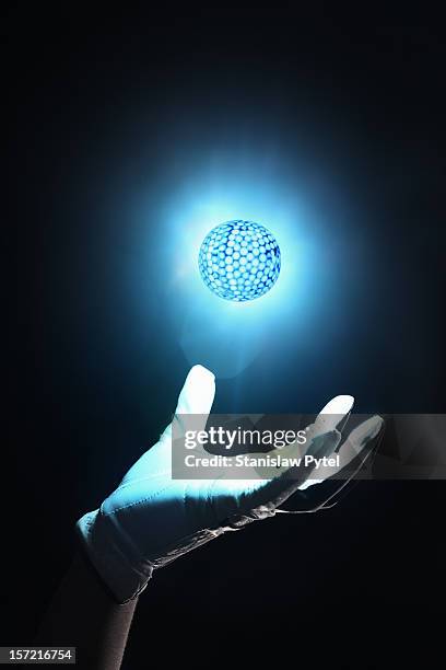 hand of golf player holding glowing ball - sports glove stockfoto's en -beelden