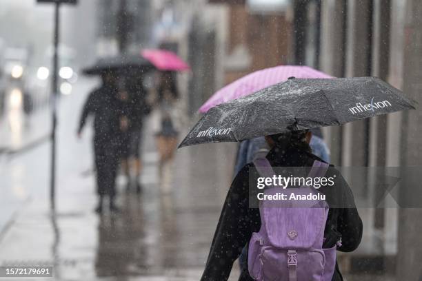 People walk on the sidewalk with umbrellas during the heavy rain in London, United Kingdom on August 02, 2023. The UK's national weather service, the...