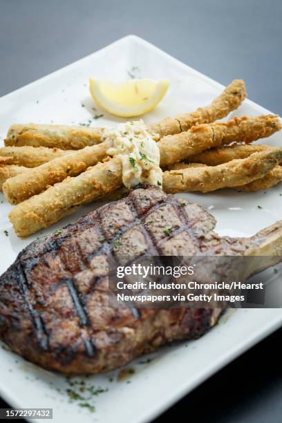 Bone-in pork shops served with fried asparagus at Katch 22 restaurant, Thursday, May 30 in Houston. Katch 22 is a joint venture between Luke Mandola...