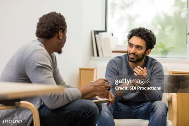 il terapeuta maschio irriconoscibile dà consigli ai giovani adulti maschi - psicoterapeuta foto e immagini stock