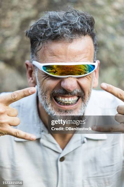 portrait of a mature man with braces wearing futuristic single-lens and mirrored glasses, opening his mouth and gesturing. concept of dentist, orthodontics, irons, treatment, smile and ugly. - ugly lips stock pictures, royalty-free photos & images