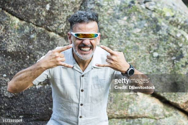 portrait of a mature man with braces wearing futuristic single-lens and mirrored glasses, opening his mouth and gesturing. concept of dentist, orthodontics, irons, treatment, smile and ugly. - ugly lips stock pictures, royalty-free photos & images