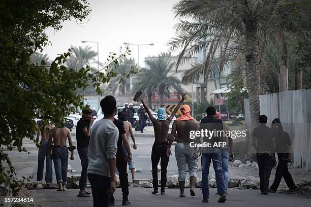 Bahraini Shiite Muslim protestor flashes the sign of victory as others take part in clashes with riot police in the village of Karranah, West of...