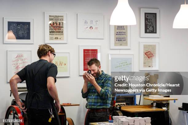 John Earles, right, checks registration on a business card while Travis Smith, looks on at Spindletop Design and Workhorse Printmakers, Wednesday,...