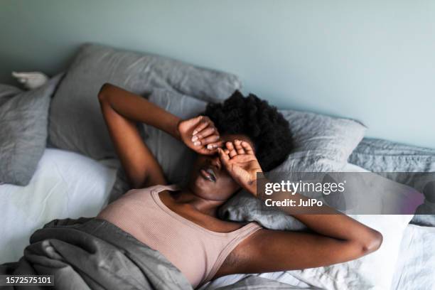 young black woman yawning and rubbing eyes in the morning - women touching herself in bed stock pictures, royalty-free photos & images