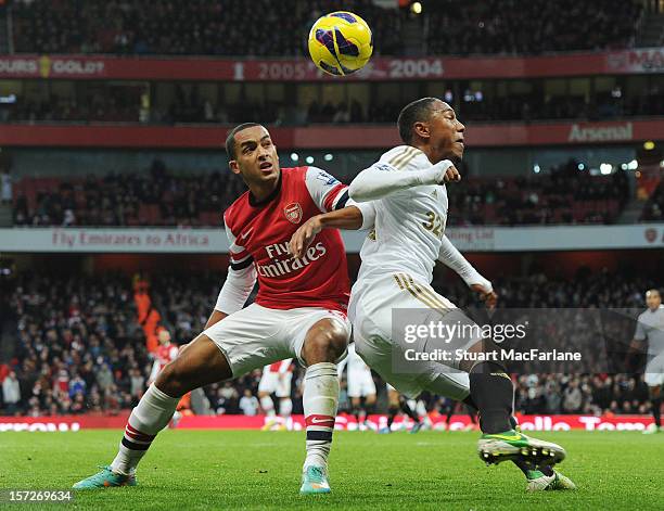 Theo Walcott of Arsenal challenged by Jonathan De Guzman of Swansea during the Barclays Premier League match between Arsenal and Swansea City, at...