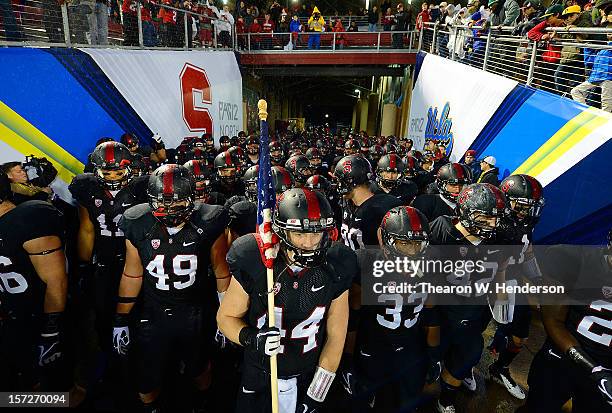 John Flacco holding a American Flag, Alex Debniak, Ben Gardner and Stepfan Taylor of the Stanford Cardinal leads their team onto the field to play...