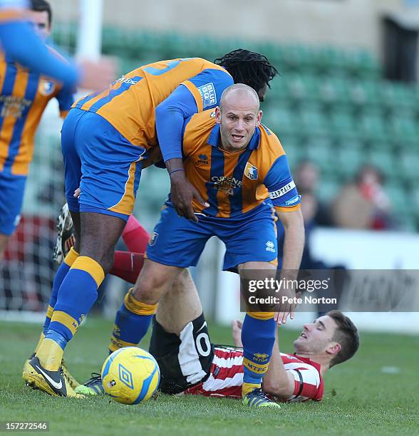 Adam Murray of Mansfield Town attempts to move away with the ball as team mate Exodus Geohaghan clashes with Jamie Taylor of Lincoln City during the...