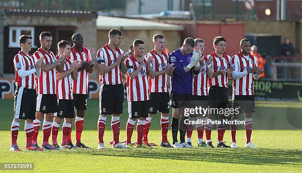 Lincoln City players observe a minutes applause in memory of former Lincoln City player Bert Linnecor prior to the FA Cup with Budweiser Second Round...