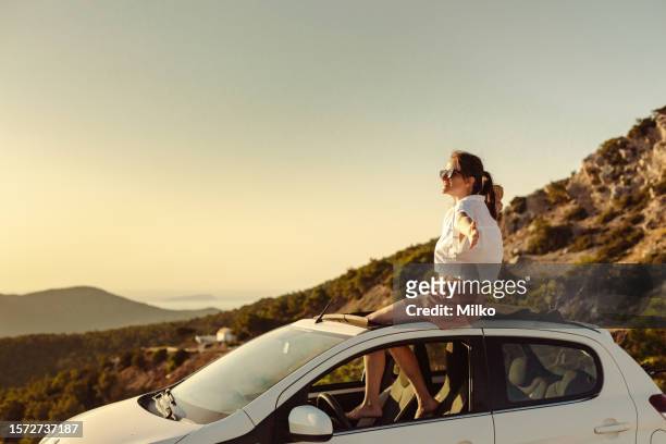 woman enjoying the beautiful sunset o na road trip - car rental stockfoto's en -beelden
