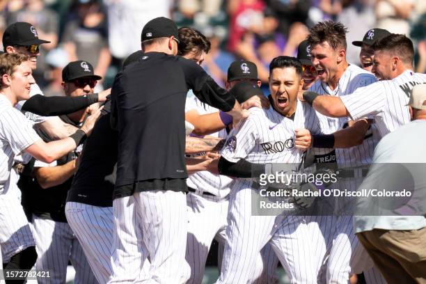 Alan Trejo of the Colorado Rockies is mobbed by teammates after hitting a walk-off home run during the eleventh inning of a game against the New York...