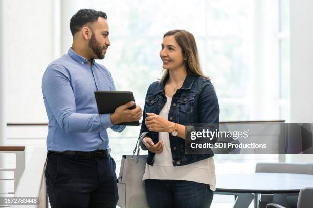 young adult male uses the digital tablet to talk to his supervisor before she leaves for the day - credit union stock pictures, royalty-free photos & images