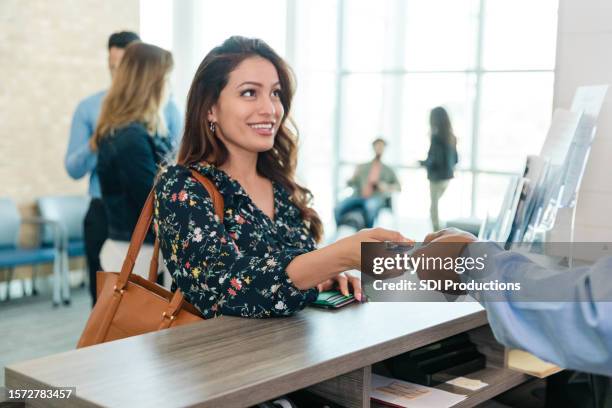 mulher entrega cartão de débito ao caixa do banco - bank branch - fotografias e filmes do acervo