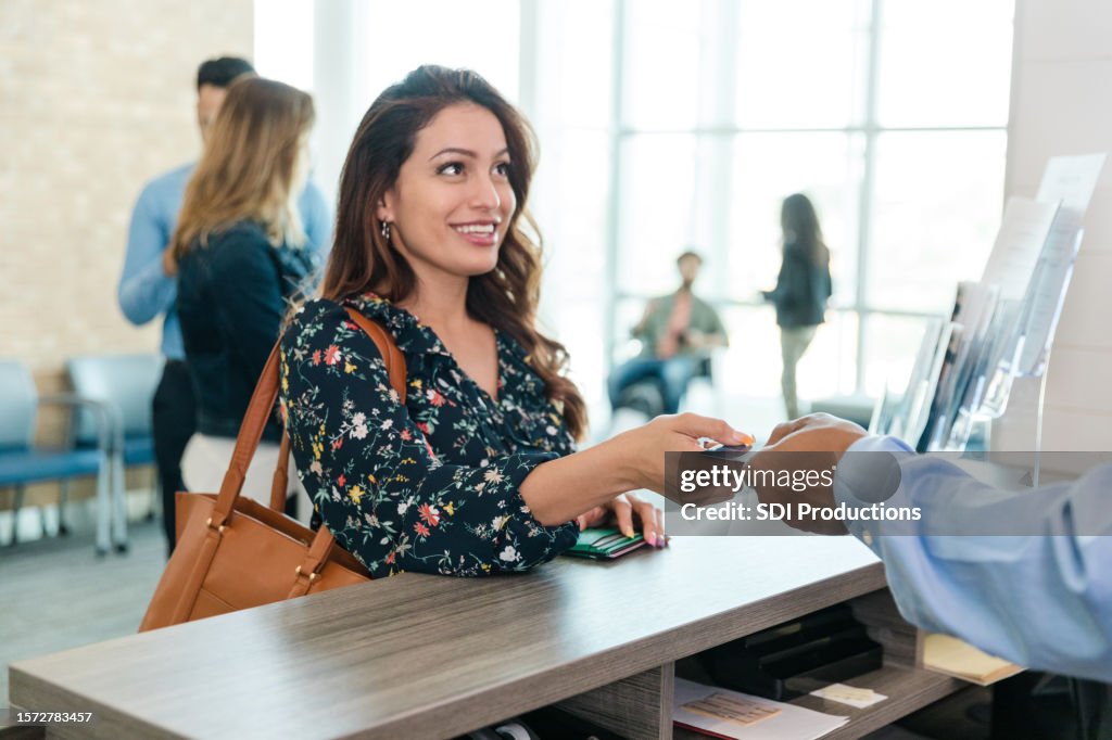 Woman hands her debit card to the bank teller