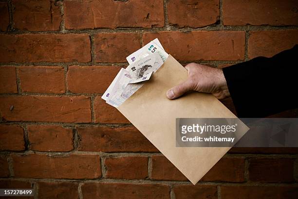 hand holding envelope and bank notes - bribing stockfoto's en -beelden