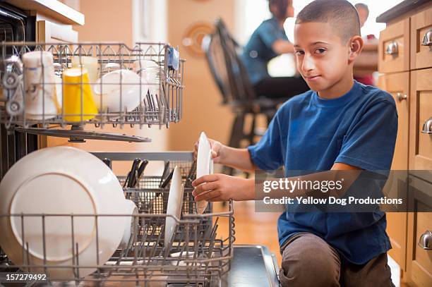 young boy loading the dishwasher - loading dishwasher stock pictures, royalty-free photos & images