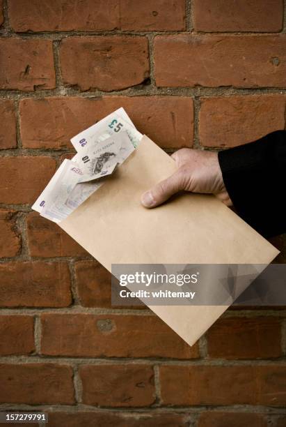 blackmailer or blackmailed? man's hand with british banknotes in envelope - manila envelope stock pictures, royalty-free photos & images