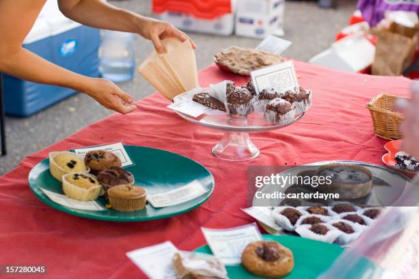 woman offers fresh pastry at charity fundraiser bake sale - bake sale stock pictures, royalty-free photos & images