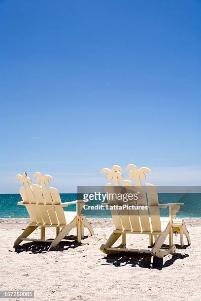 two white wooden beach chairs on sand with ocean - captiva island florida stock pictures, royalty-free photos & images