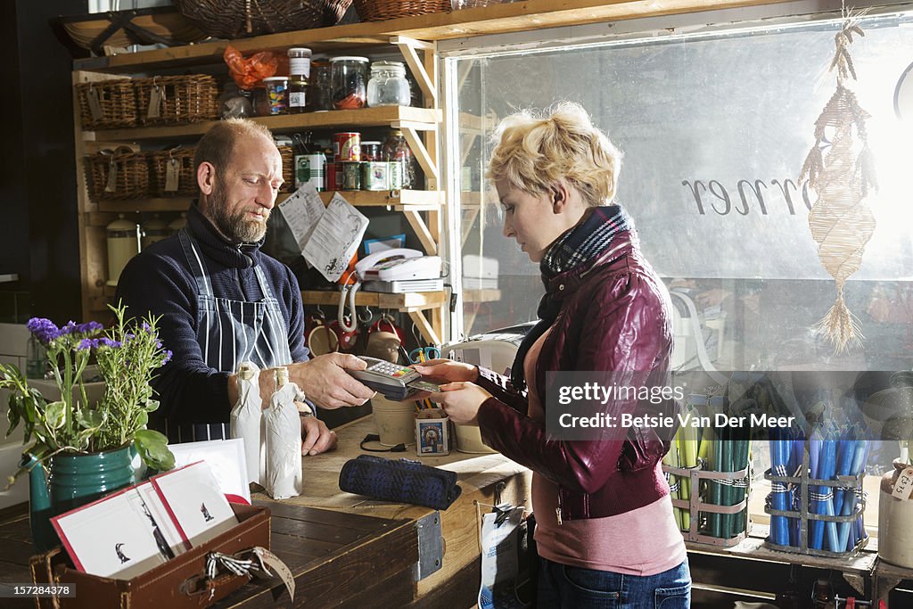 Shop owner hands pin acceptance device to customer