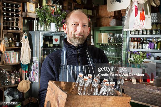 shop owner holding box of glas bottles in shop. - glas bottle imagens e fotografias de stock