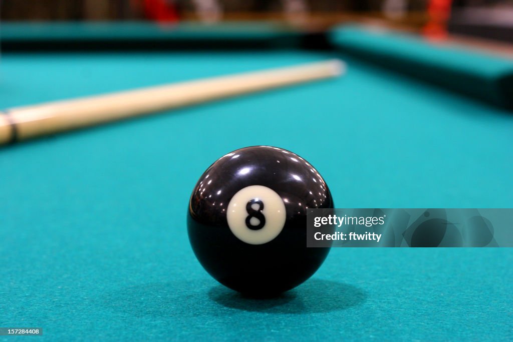 Close up of 8 ball on green felted pool table