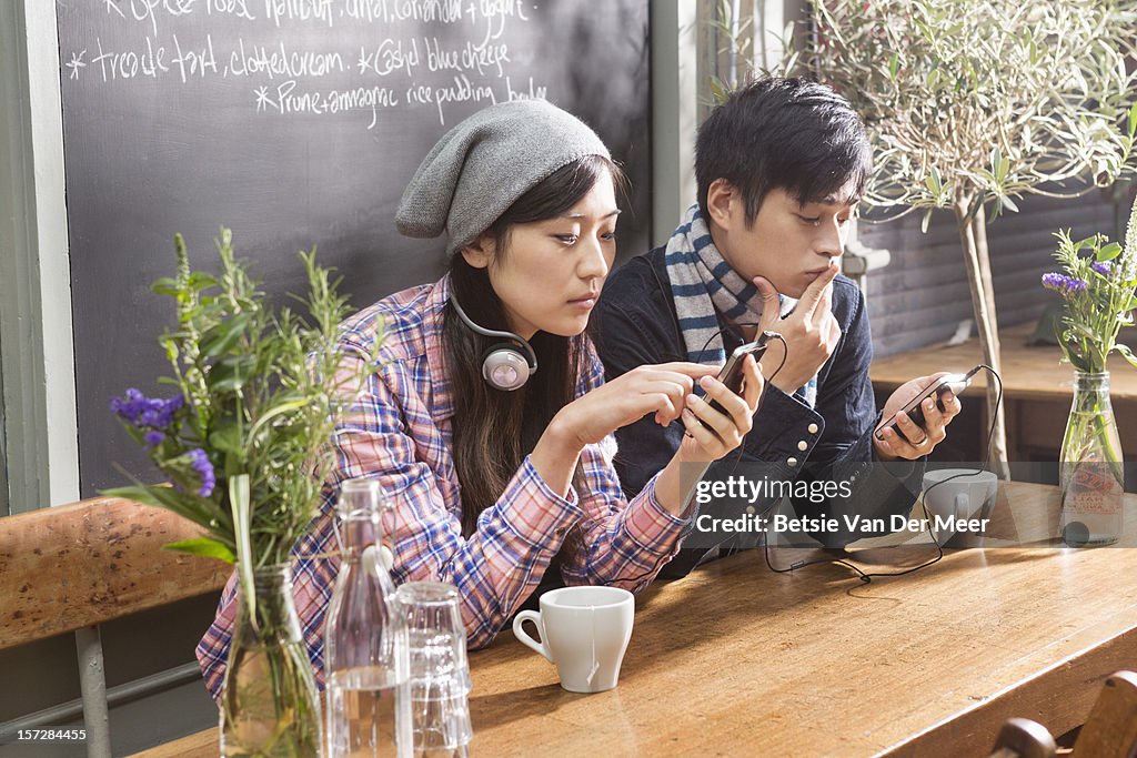 Asian couple looking at their mobile phones.
