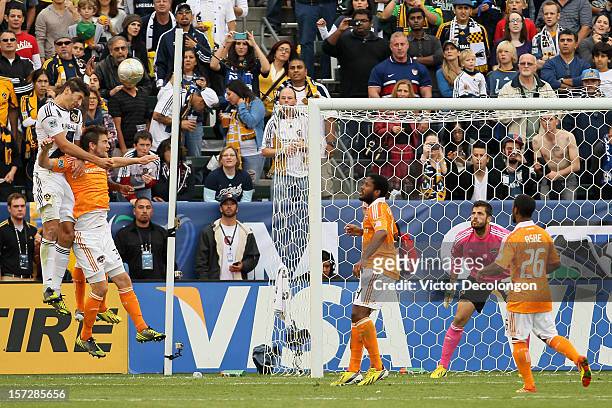 Omar Gonzalez of Los Angeles Galaxy heads in a goal over Bobby Boswell and Kofi Sarkodie of Houston Dynamo in the second half in the 2012 MLS Cup at...