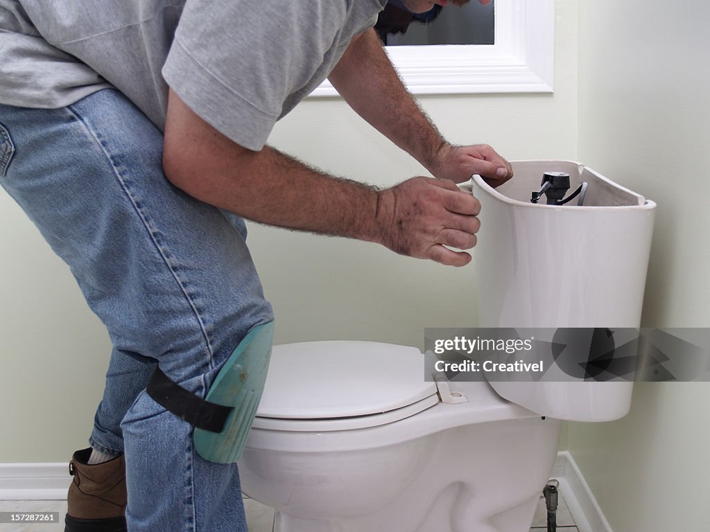 Plumber at work repearing toilet