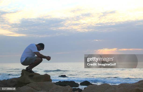 joven hombre caucásico de rezar junto al mar - rogar fotografías e imágenes de stock