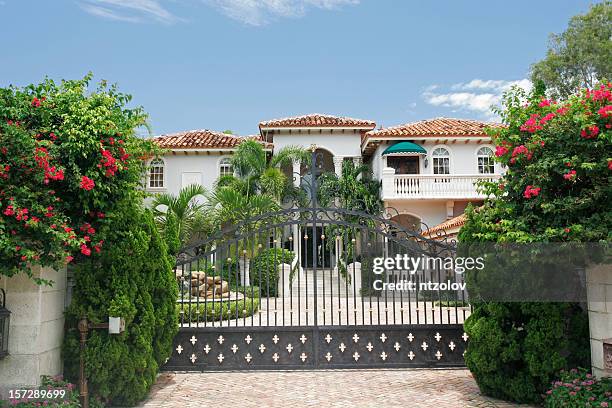 mansion behind a gate surrounded by tropical greenery - miami house stock pictures, royalty-free photos & images