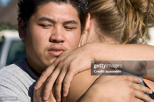 asian teenage man hugging blond girl, crying - man crying tears stock pictures, royalty-free photos & images