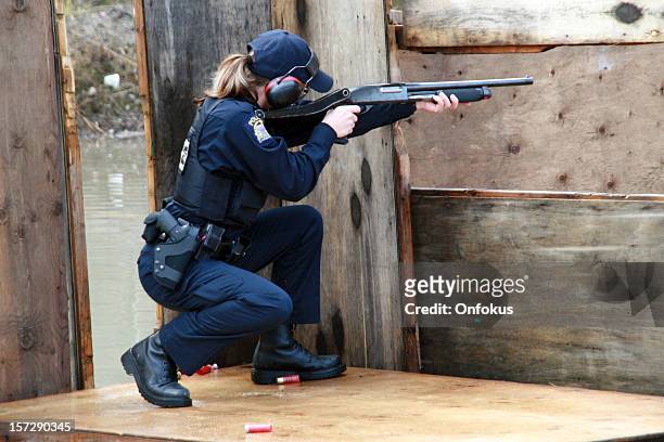 woman police officer shooting shotgun at the practice field - shotgun stock pictures, royalty-free photos & images