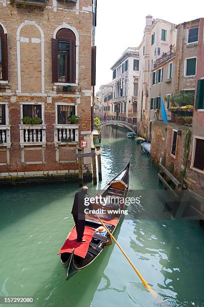 gondola in venice going down a small residential canal - gondolier stock pictures, royalty-free photos & images