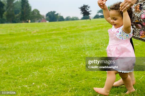 smiling baby girl learns how to walk on grass with mother - barefoot running stock pictures, royalty-free photos & images