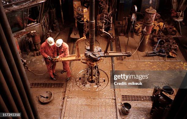 two roughnecks working on oil rig platform drill floor - oliewerker stockfoto's en -beelden