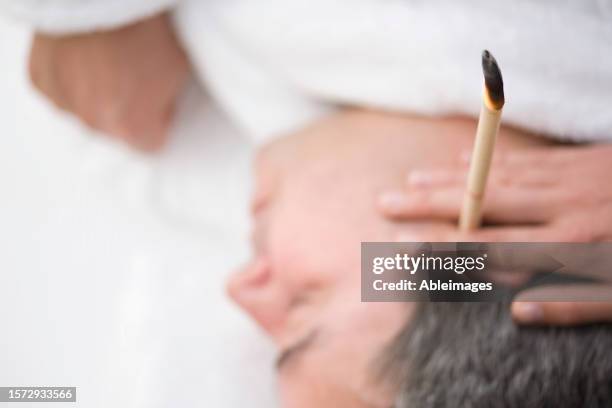 close up of man's head with burning ear candle - ear wax stock pictures, royalty-free photos & images