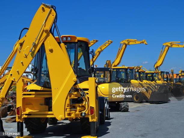 diggers in una riga sul parcheggio industriale - construction vehicles foto e immagini stock