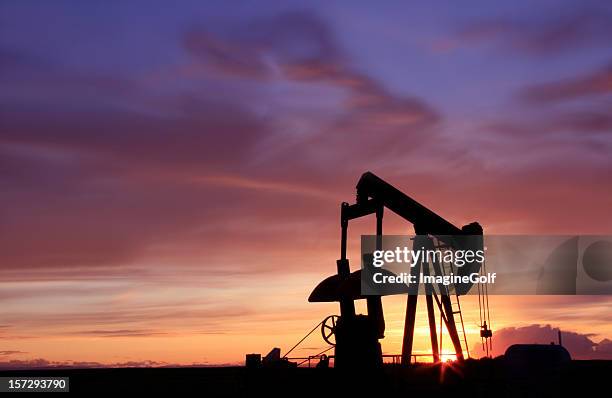 silhouette of an oil industry pumpjack in canada - hefboom stockfoto's en -beelden