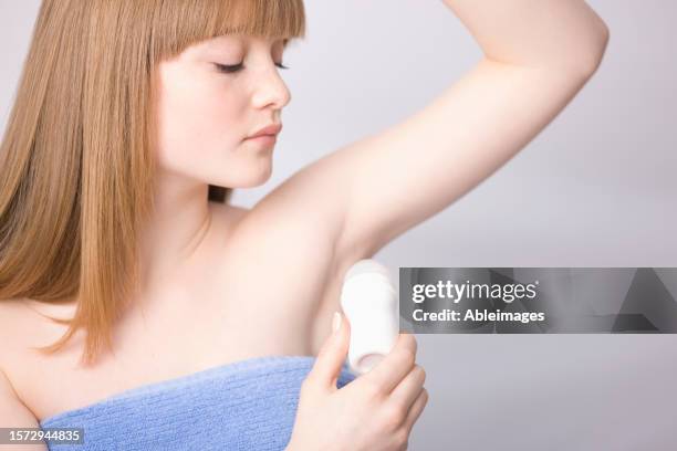 close up of young woman applying deodorant under armpits - body odour stock pictures, royalty-free photos & images