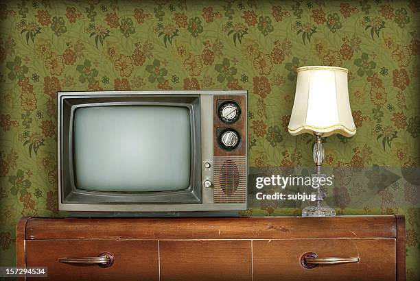 retro living room with a tv and a lamp atop a wooden desk - sixties stockfoto's en -beelden