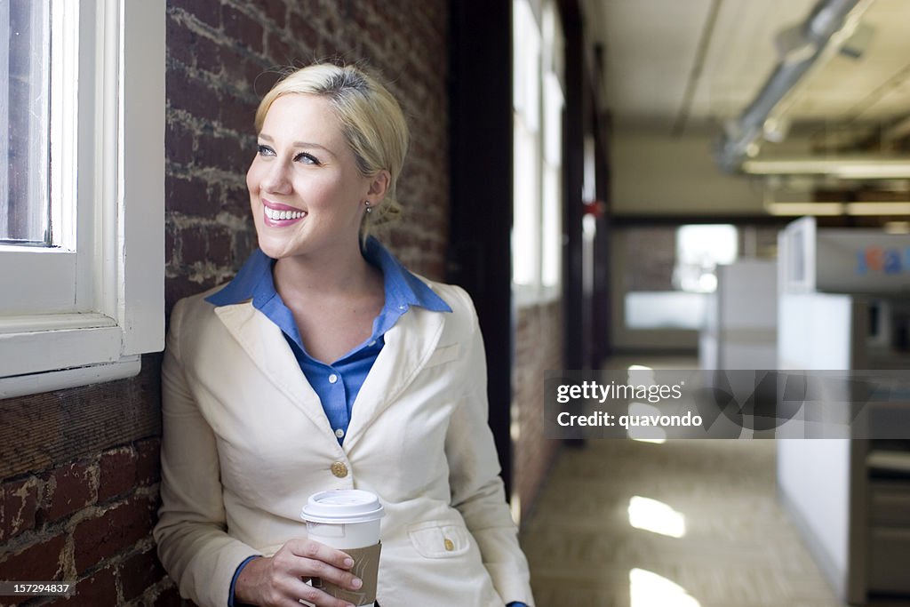 Beautiful Young Businesswoman Taking Coffee Break in Office Hallway, Copyspace