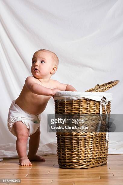 young baby looking in a laundry basket feeling guilty - baby standing stock pictures, royalty-free photos & images