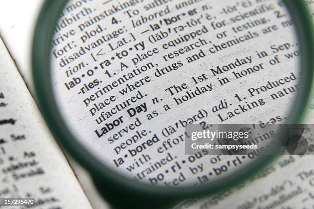 a magnifying glass showing the definition of labor day - may day international workers day stockfoto's en -beelden